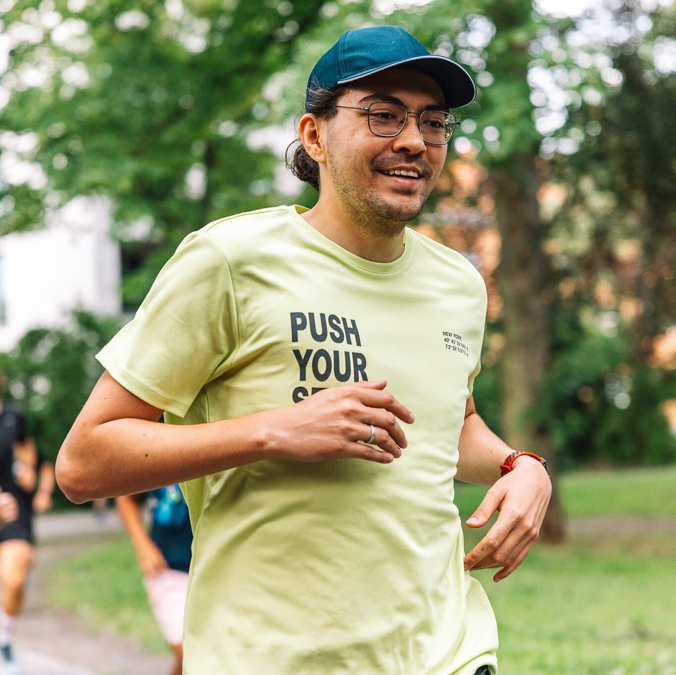 A man running outdoors in a park, wearing a motivational Push Your slogan shirt.